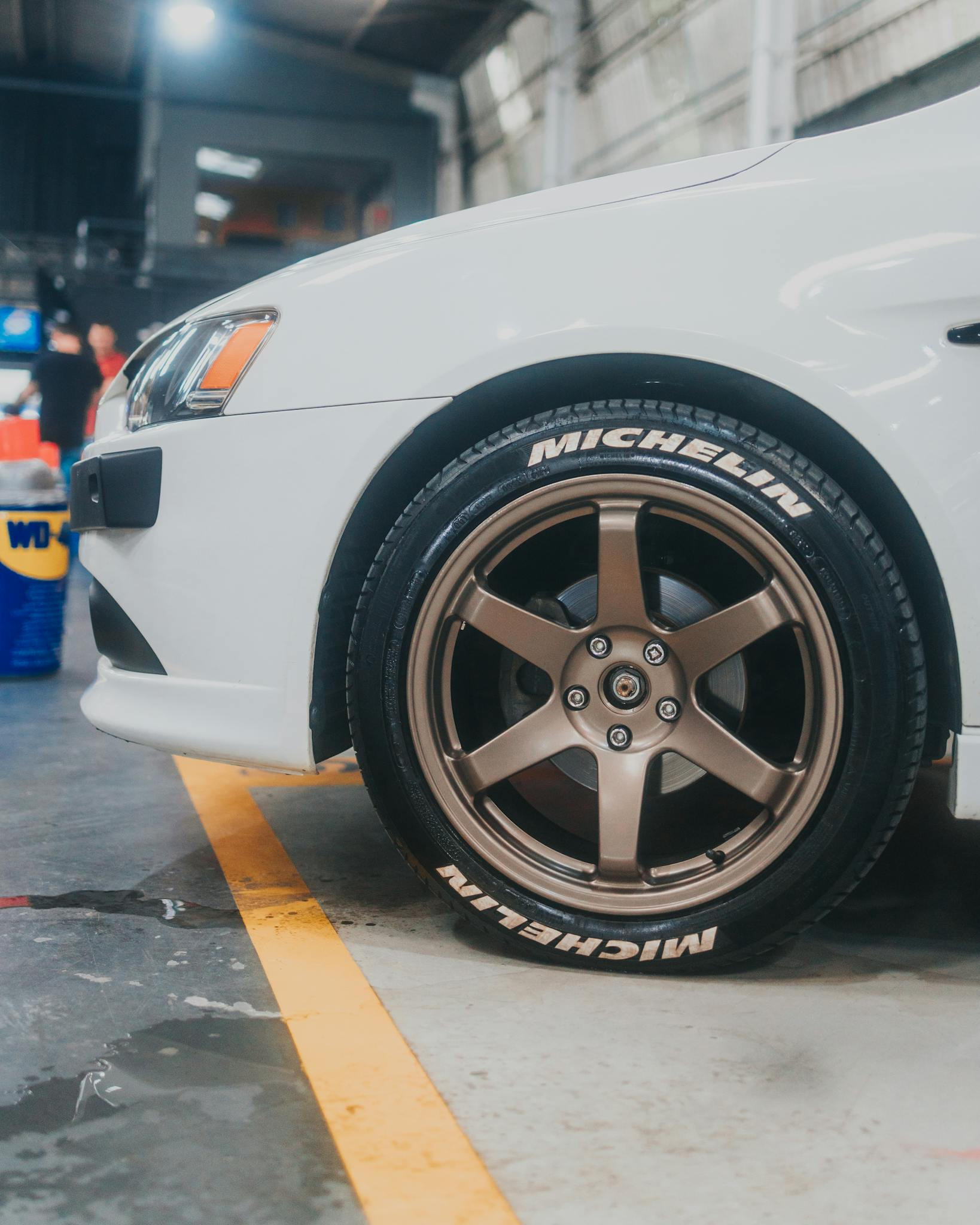 Focused shot on a car wheel and tire inside a spacious garage environment.