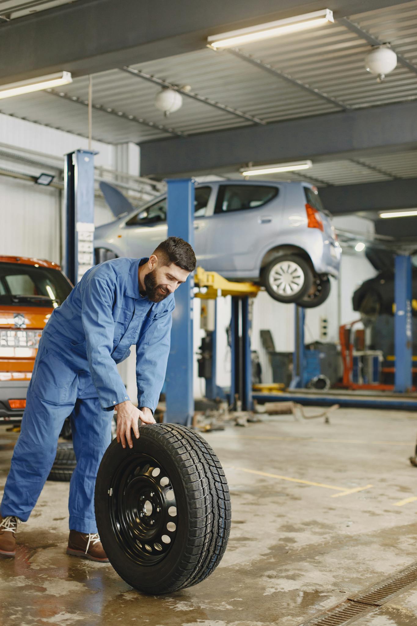 Mechanic handling a tire in a busy automotive repair workshop.